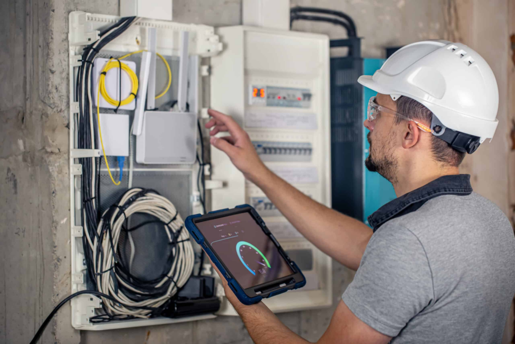 Eletricista com capacete inspeciona quadro elétrico durante laudo elétrico em condomínio